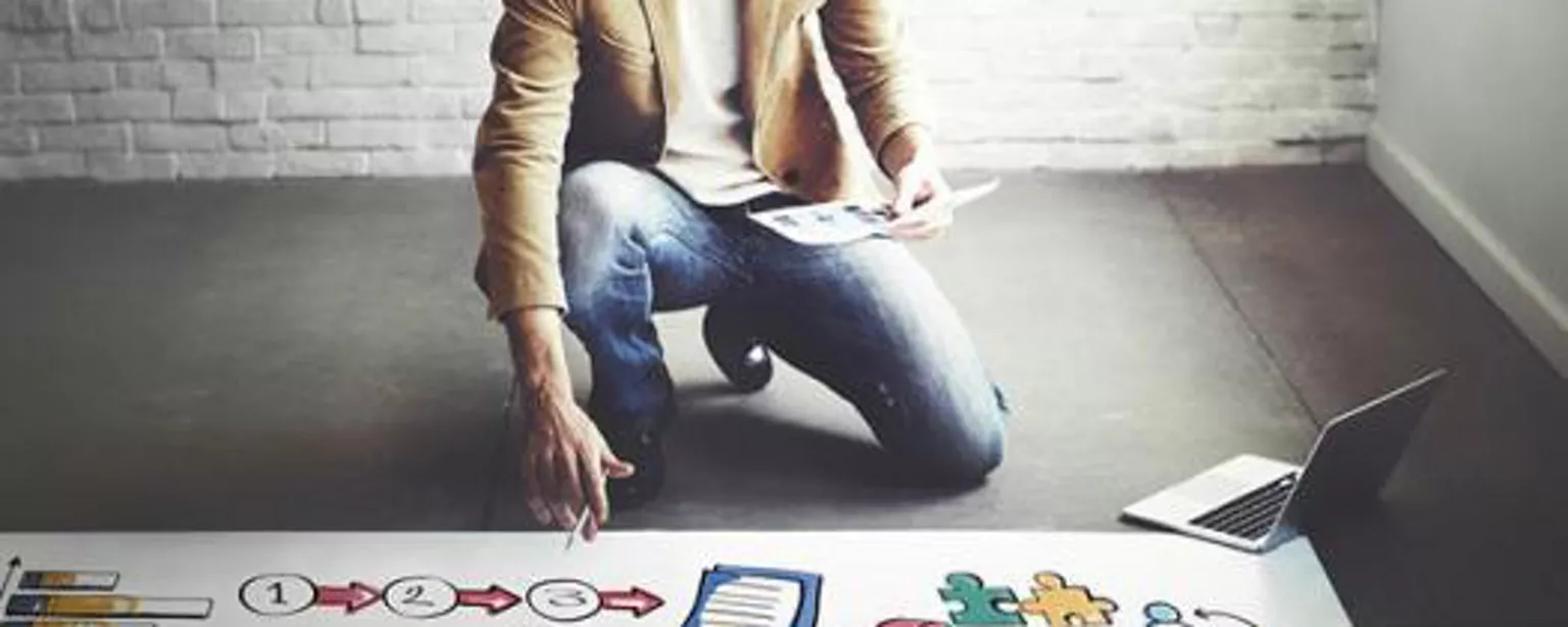 Man leaning over poster with creative symbols