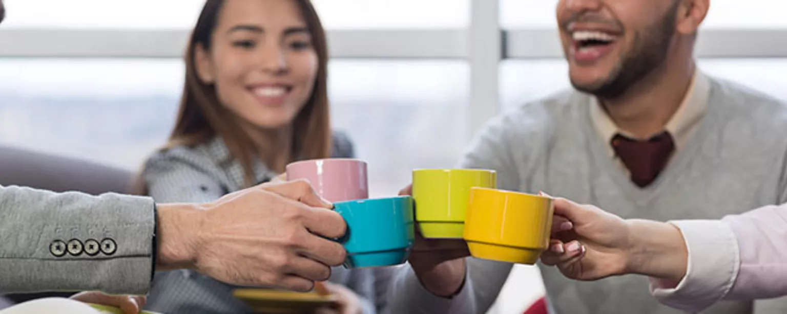 Happy employees drinking coffee in a meeting.