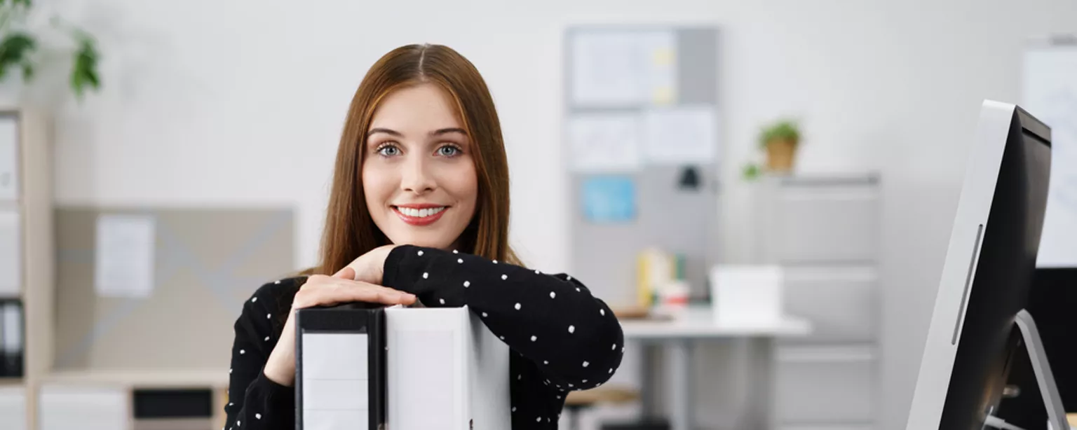 The Latest Salary Scoop for a Data Entry Specialist — Photo of a woman at a desk with a computer and two binders.