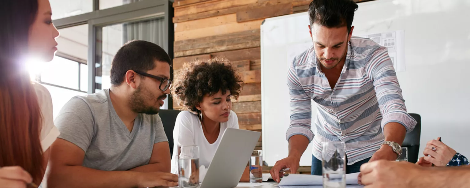 A group of workers sitting around a table looking at sheets of information.