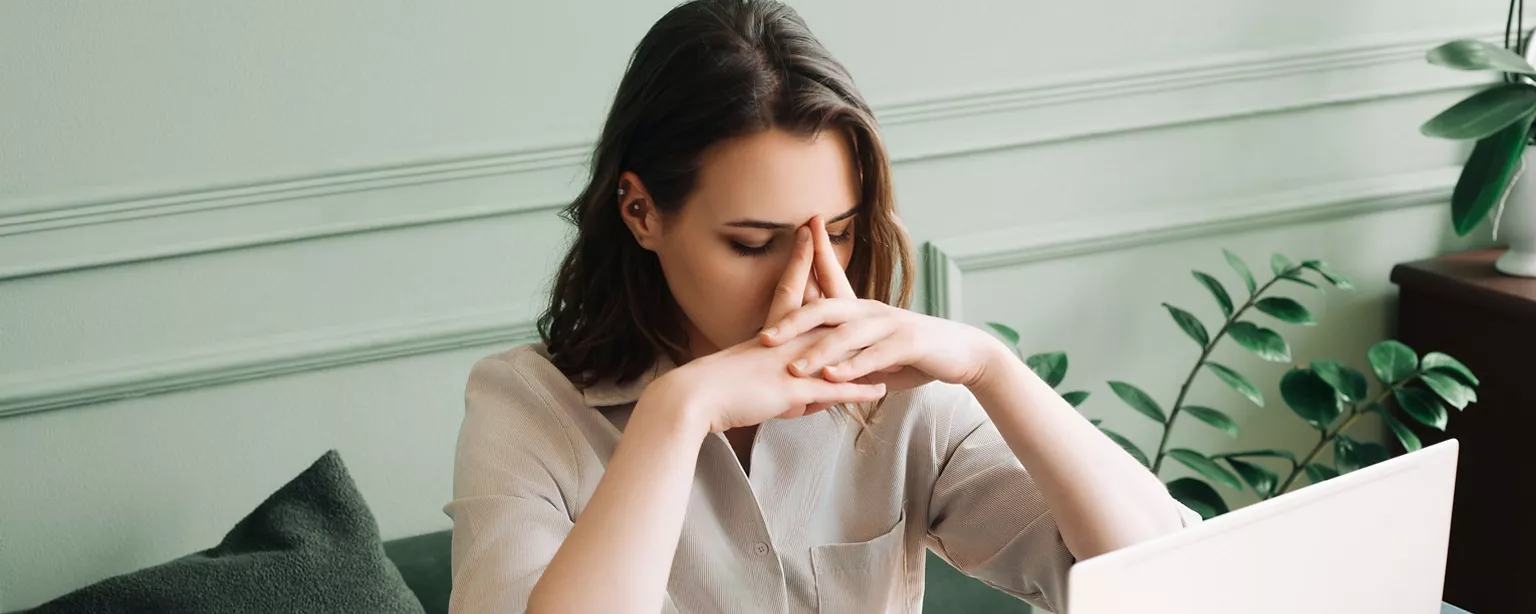 A woman sits at her office desk in a dejected pose as she processes the fact that she has been demoted at work.