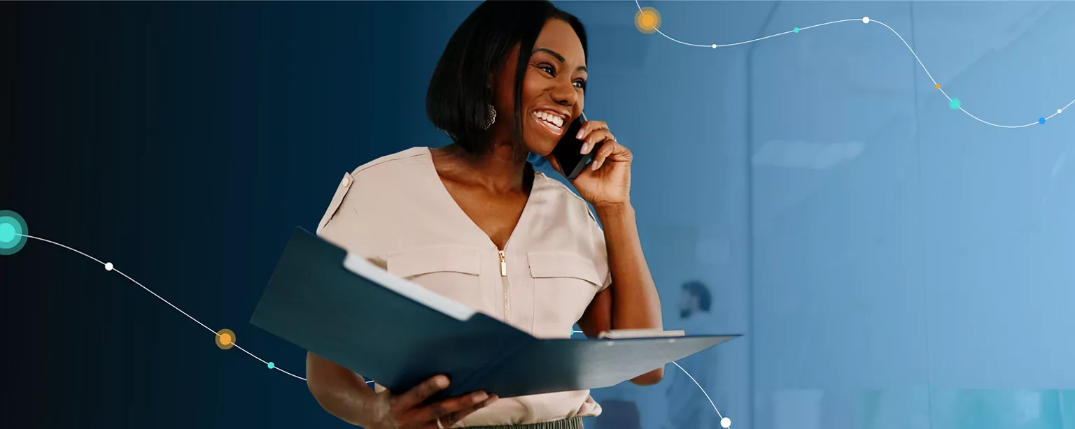 A healthcare professional in a white shirt smiles while talking on the phone and holding a binder.