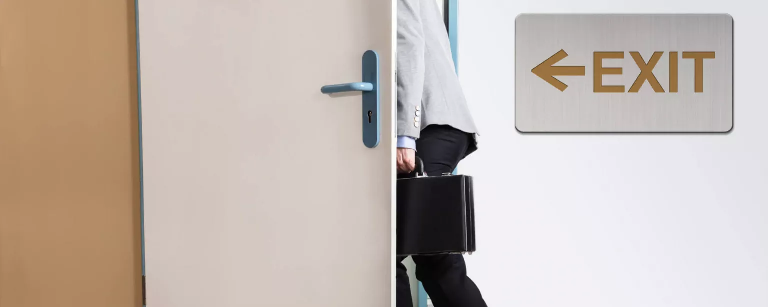 Image of a new employee leaving through a door next to an exit sign.