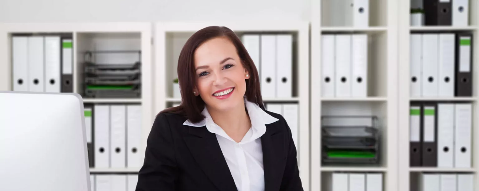 Your Comprehensive Guide to Entry-Level Accounting Jobs — woman working with calculator in front of shelves of notebooks