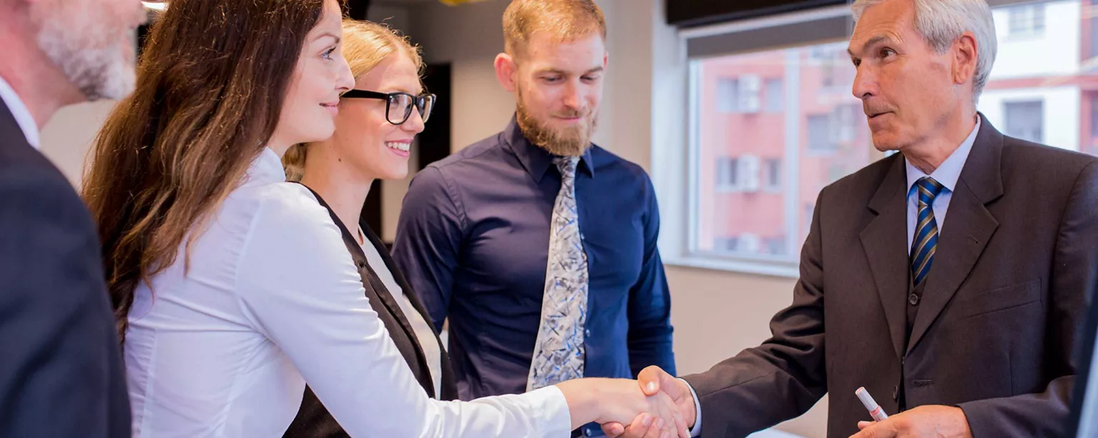 Businessmänner und -frauen geben sich die Hand.