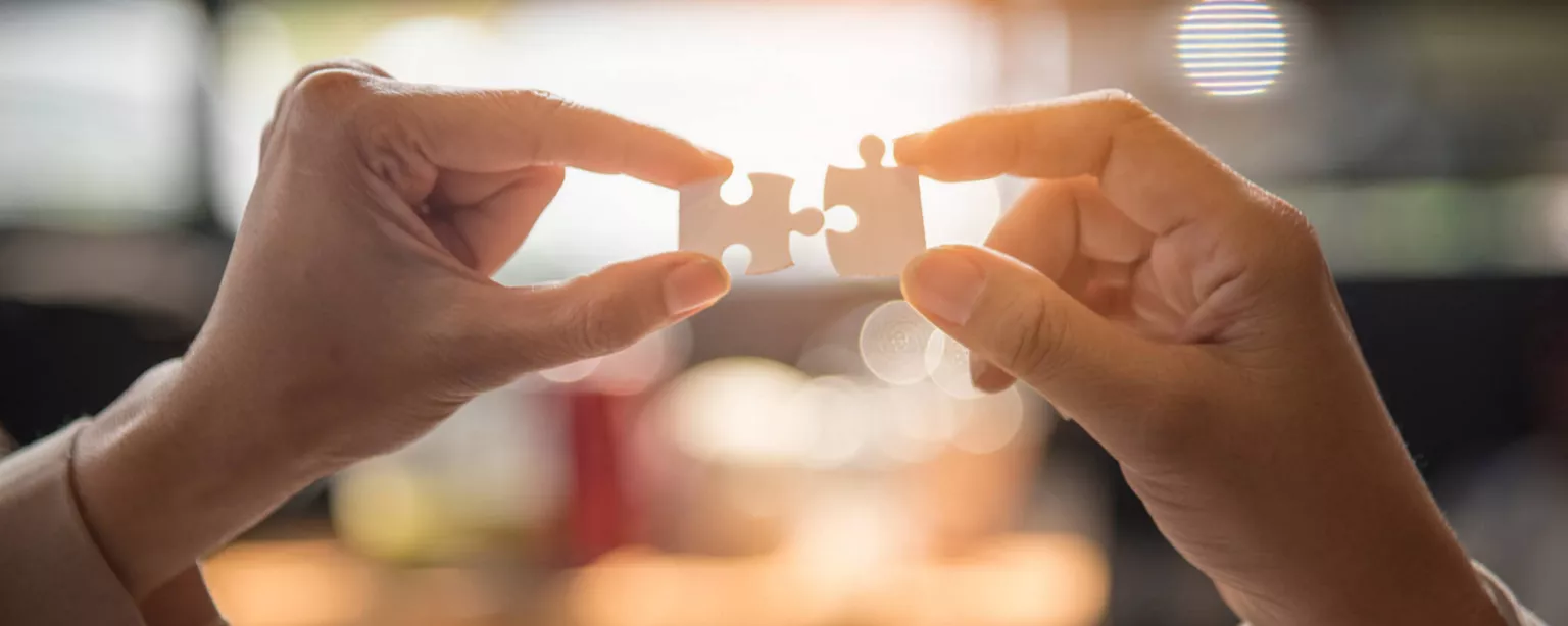 How to Work in Partnership With Your Executive Assistant — image of two hands holding puzzle pieces that fit together