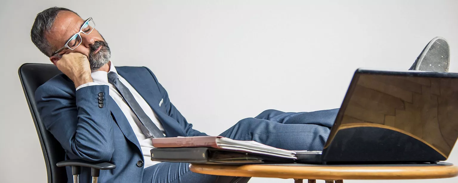 Businessman sitz am Schreibtisch und schläft.