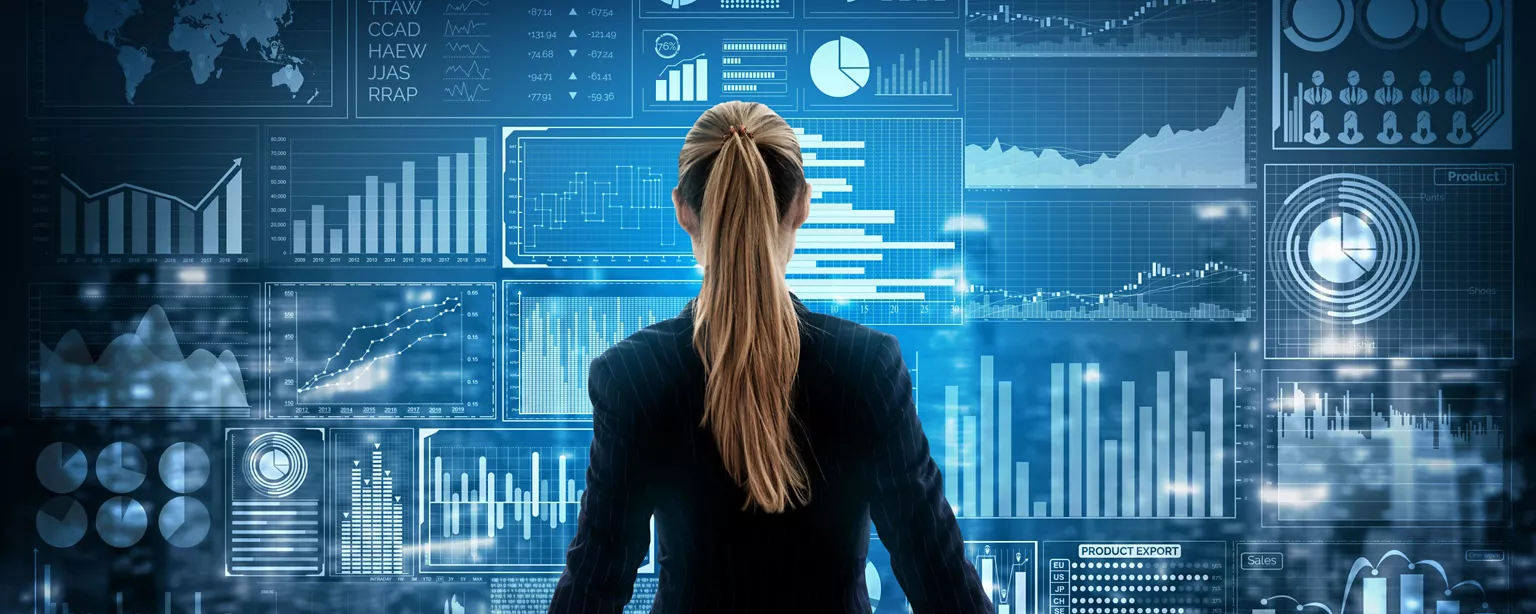 A professional reviews a wall of digital financial dashboards filled with charts and analytics