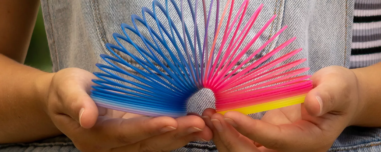A multicolored plastic coil, a toy, is set up against a blue background.