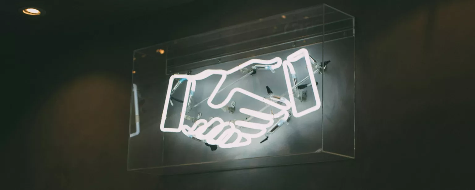 Neon-Reklame auf der sich zwei Hände schütteln
