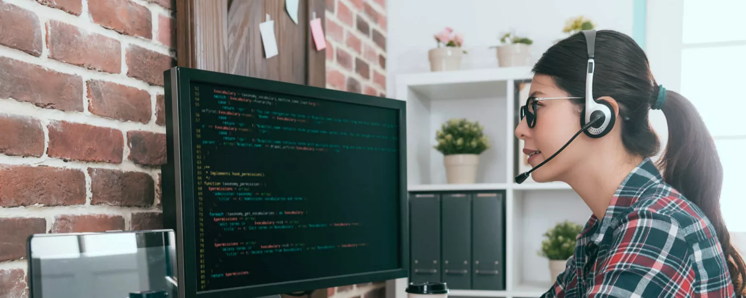 A woman wearing headphones works at a computer.