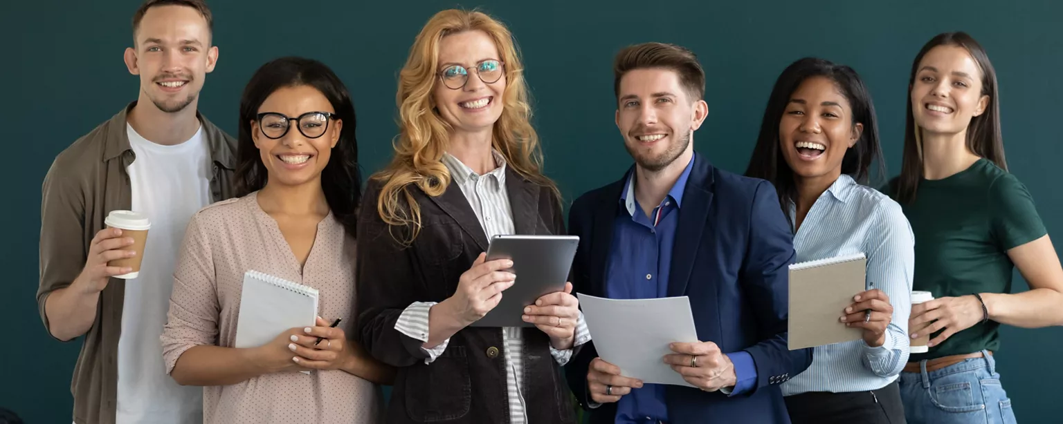 Helpful team members of an employment agency smile as they stand side by side to greet potential clients.