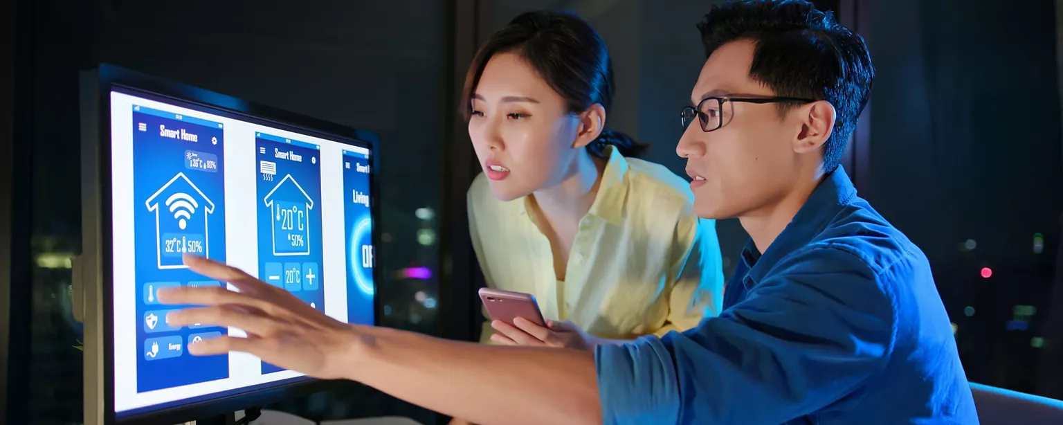 Two UX designers look at the display on a computer monitor.