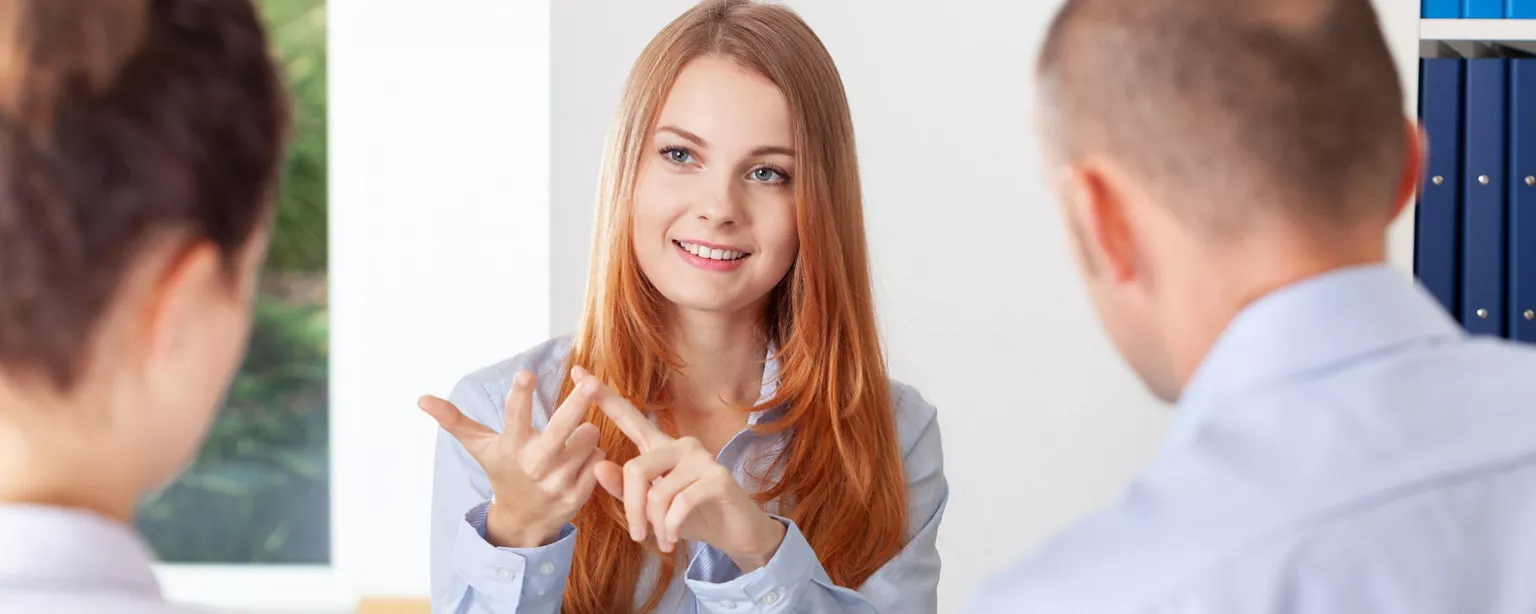 A young woman interviewing for a job uses her fingers to count out the reasons she wants to work for that company.