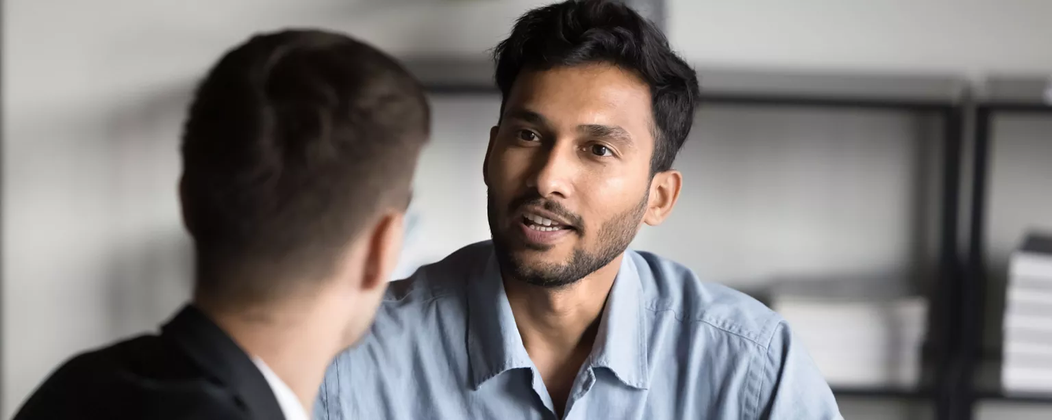 An office worker and his manager engage in a conversation in the workplace.