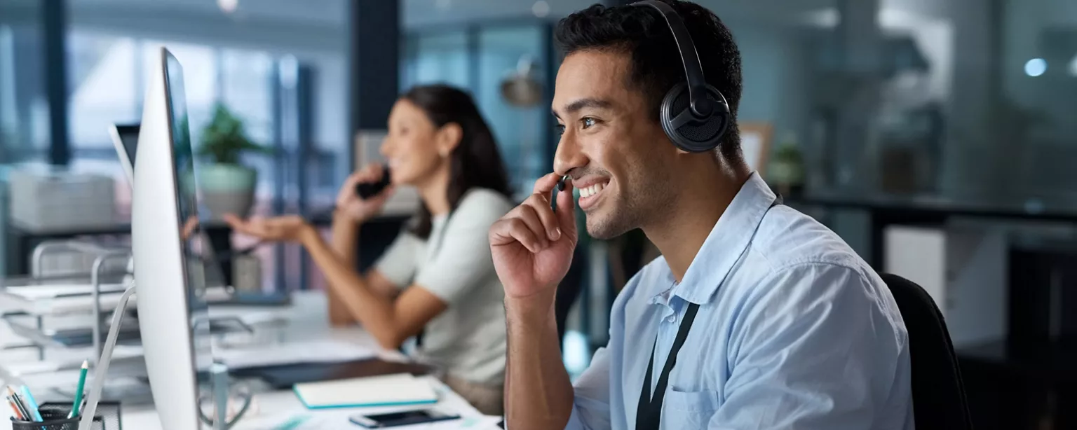 Two customer service specialists work side by side in a call center.