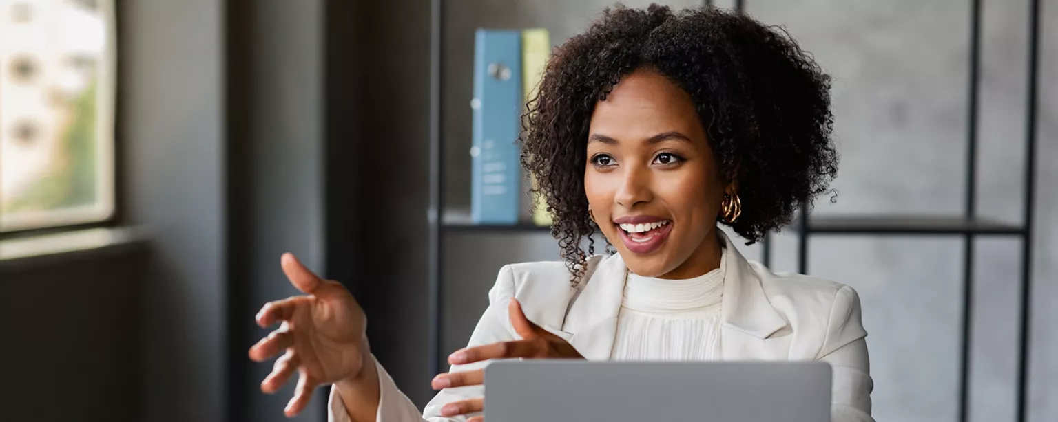 A professional woman enthusiastically gestures while discussing something in an office.