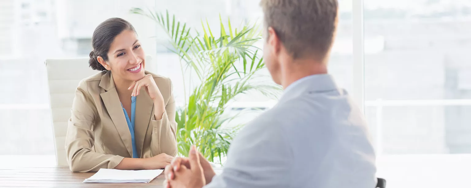 An employee discusses a raise with his manager as she smiles while listening.