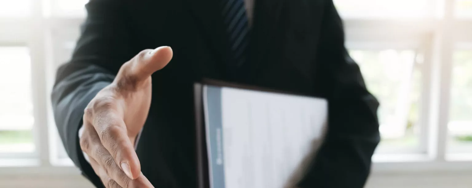 Closeup image of an employer who understands how to hire reaching out to shake a hand.