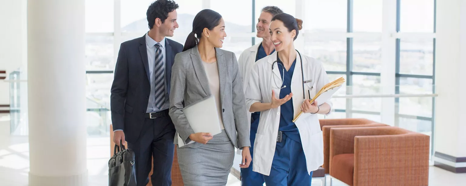 A team of medical professionals talk while walking in a hospital environment.