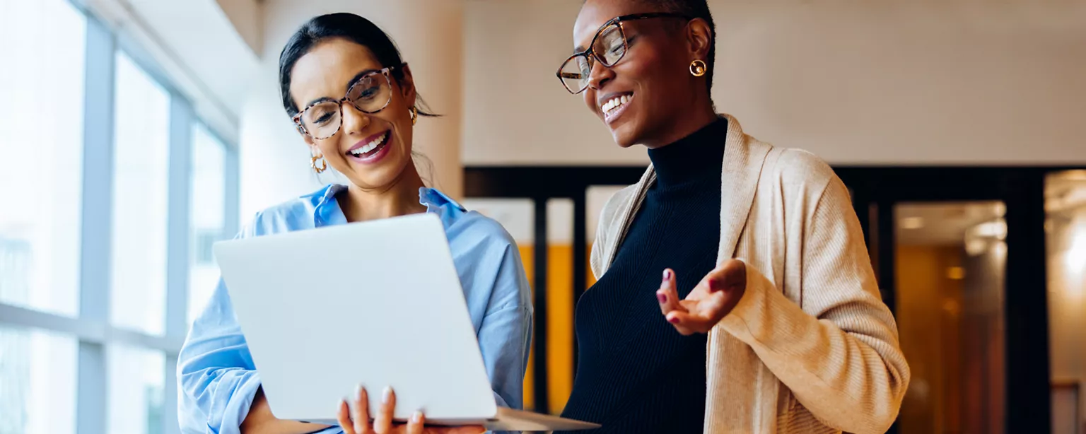 two workers looking at a laptop at work discussing career development programs
