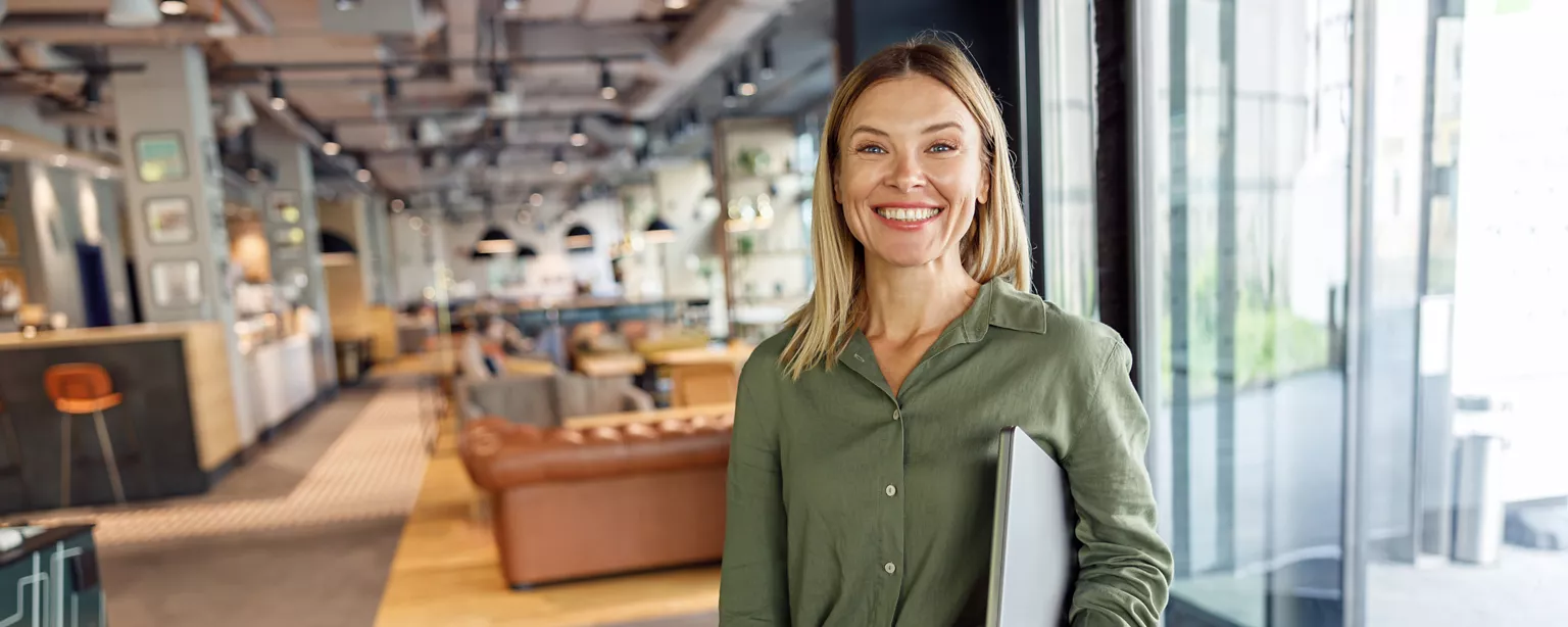 a woman working in payroll looking at the camera smiling while in a modern office setting