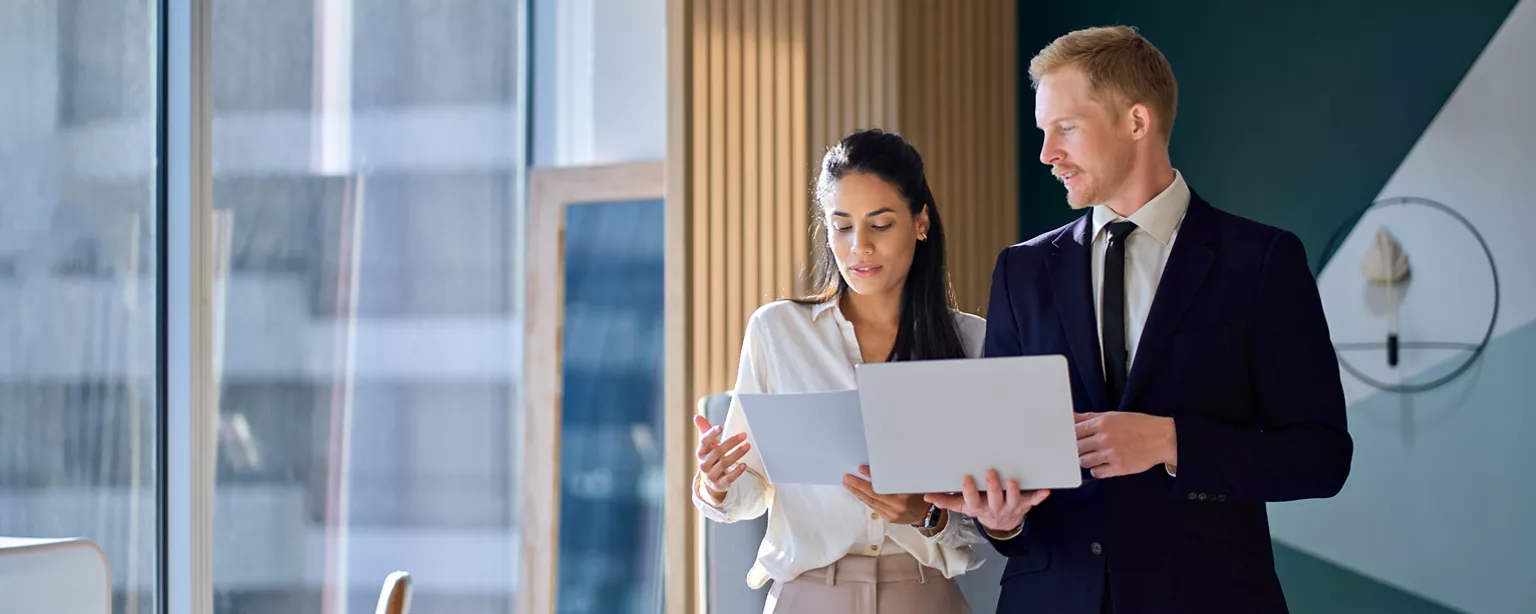 two professionals wearing business suits around reviewing the 2026 Canada Salary Guide from Robert Half