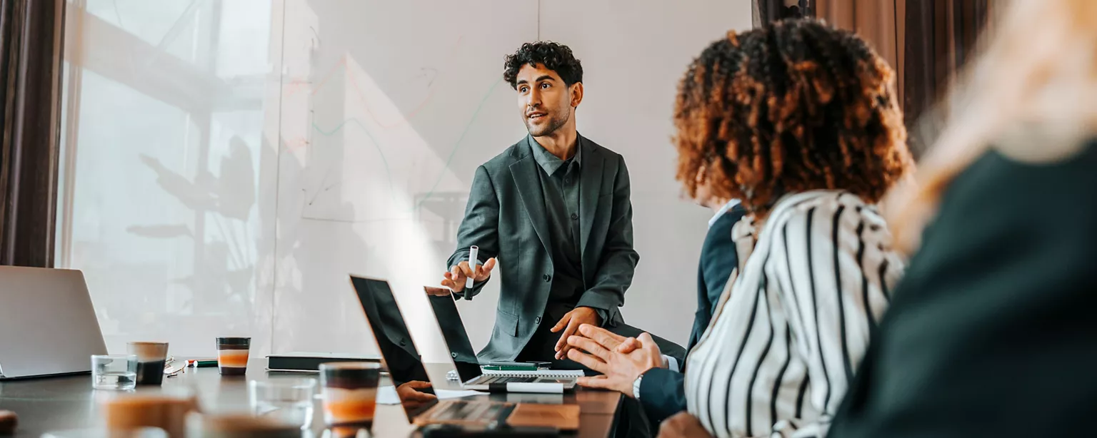 A person speaking at the front of a boardroom meeting