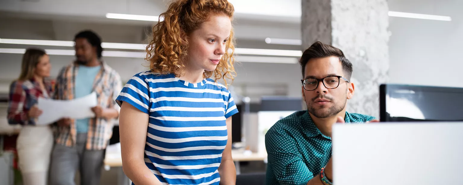 Deux employés examinent les résultats d'une enquête sur la population active réalisée par Statistique Canada sur un écran d'ordinateur dans un bureau.