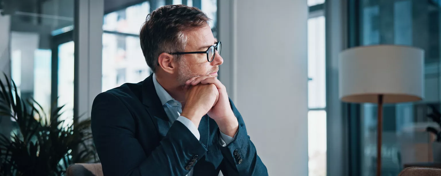 business man in his office looking thoughfully out the window