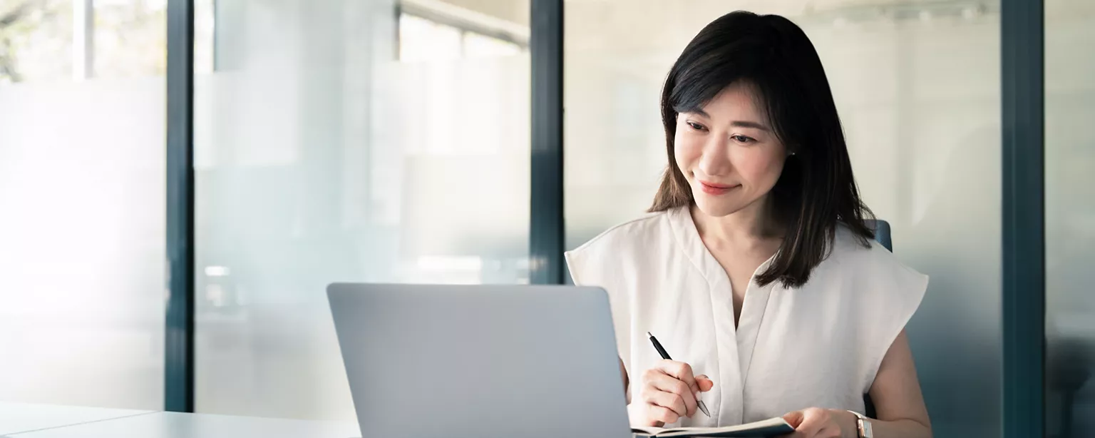 Woman in an online meeting, taking notes on a notepad