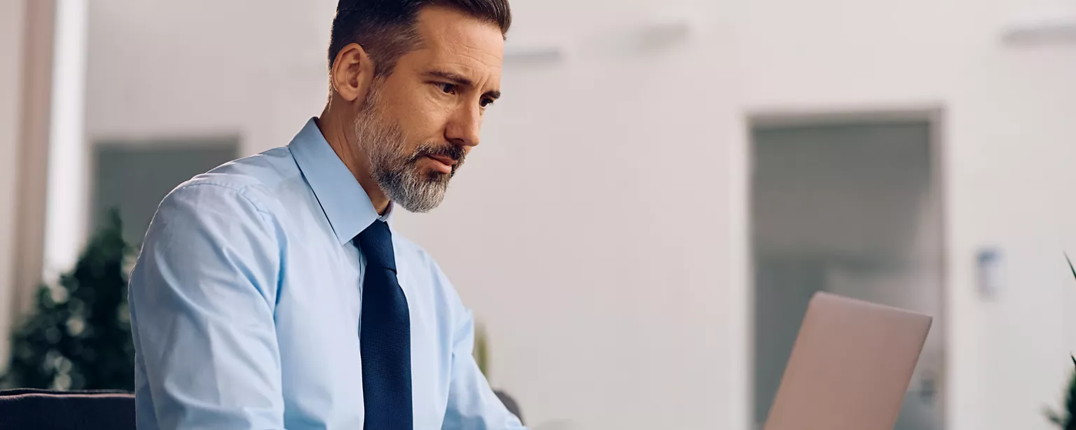 Man, wearing a tie, looking at his laptop