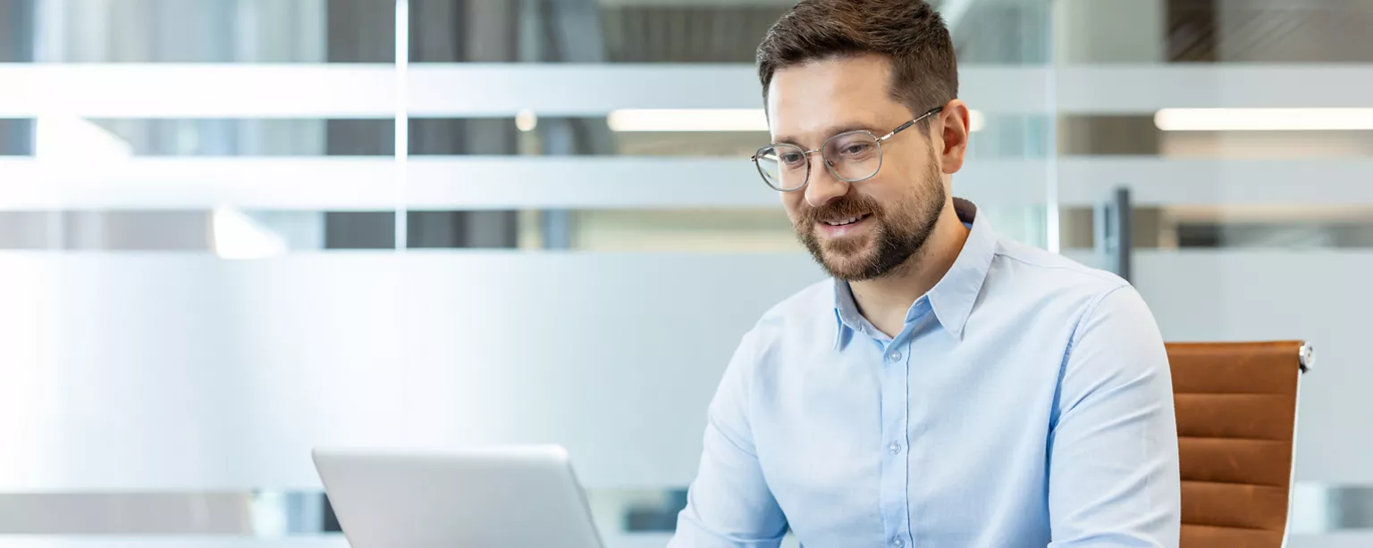 man in an office sat in front of his laptop