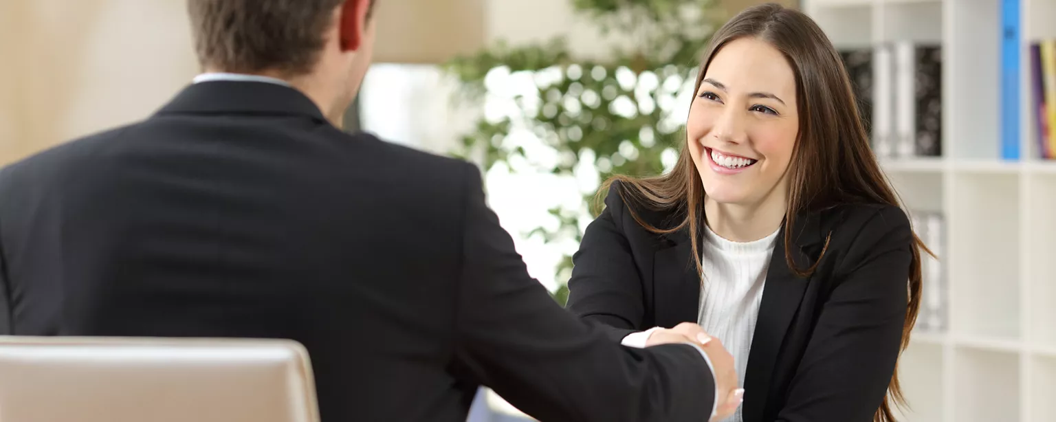 A man and woman in business suits shaking hands.