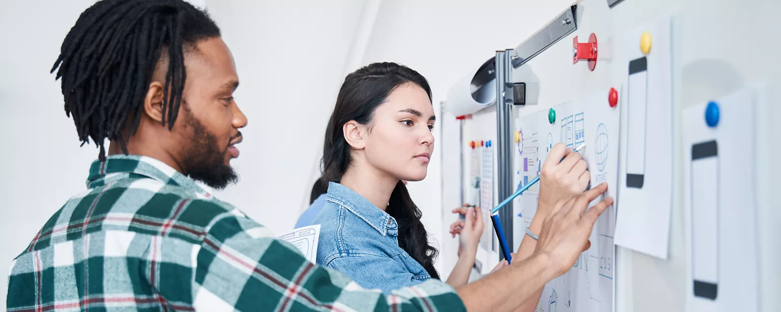 Une équipe regardant des documents sur un tableau blanc, discutant des tendances en marketing