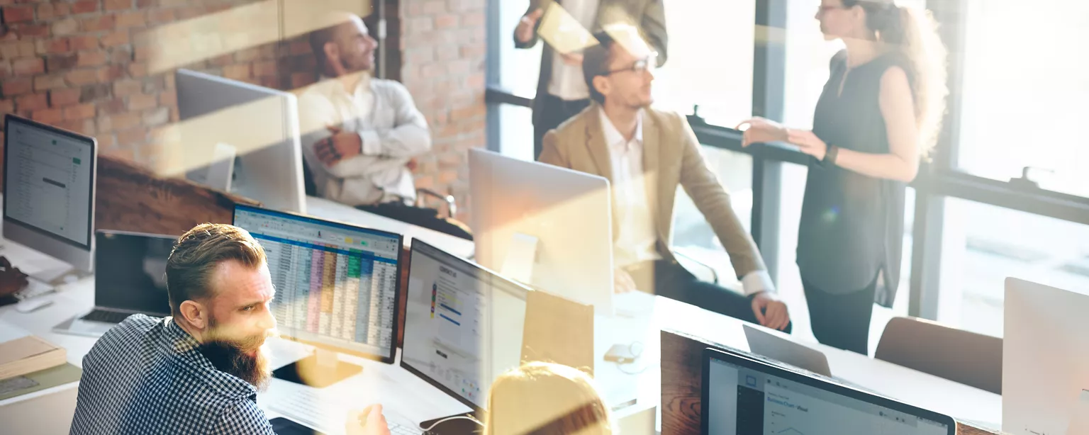 workers in an office talking and on computers