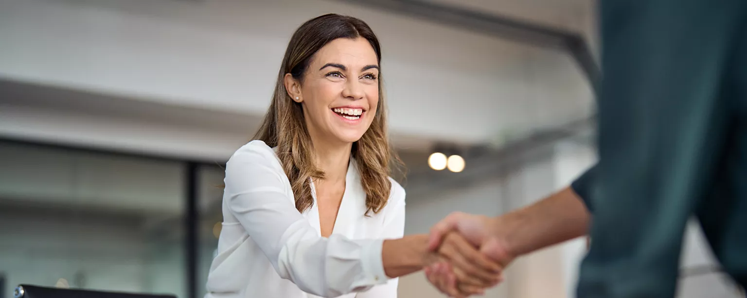 Woman shaking hands with her interviewer, ready to answer why she wants to work for the company