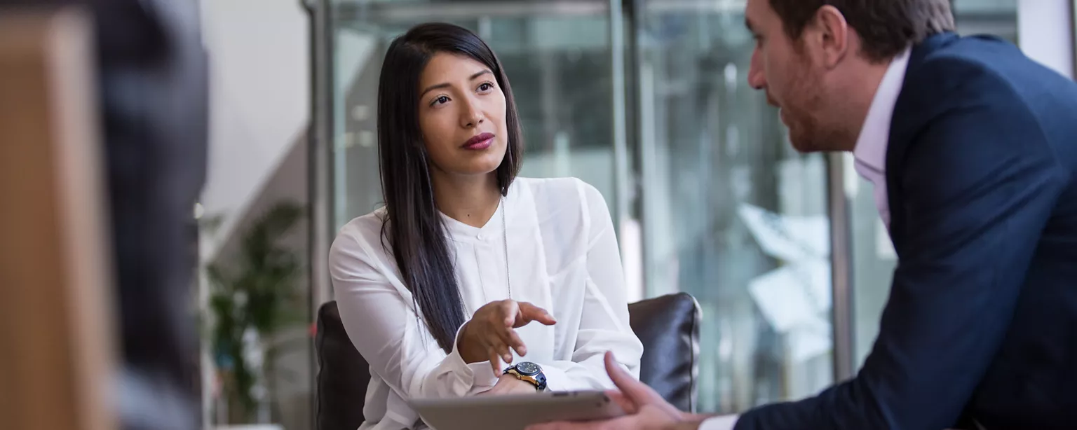 A young woman talking to a man who is looking at some documents during a job interview