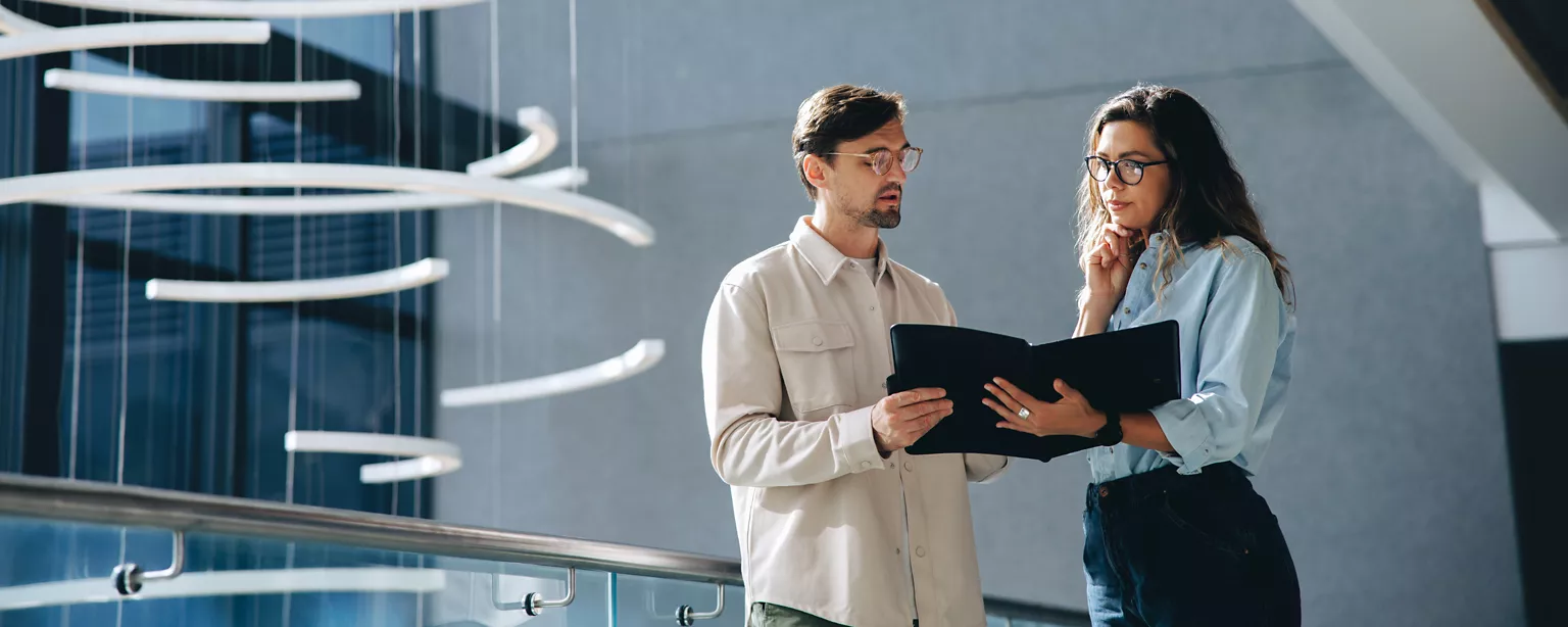 Two job seekers looking at and discussing a report about the hiring market outlook in Canada