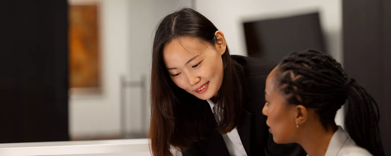 Two women talking in the office, one offering feedback to the other.