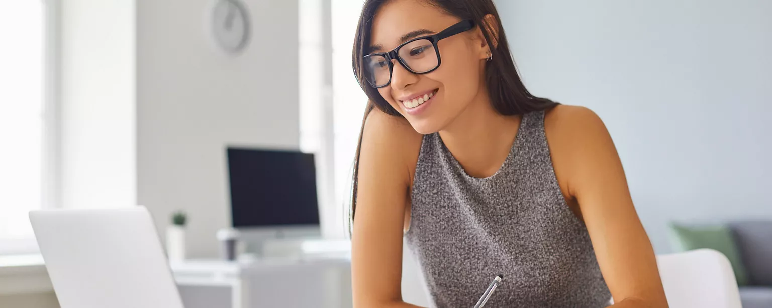 A woman smiling while looking at her laptop. 