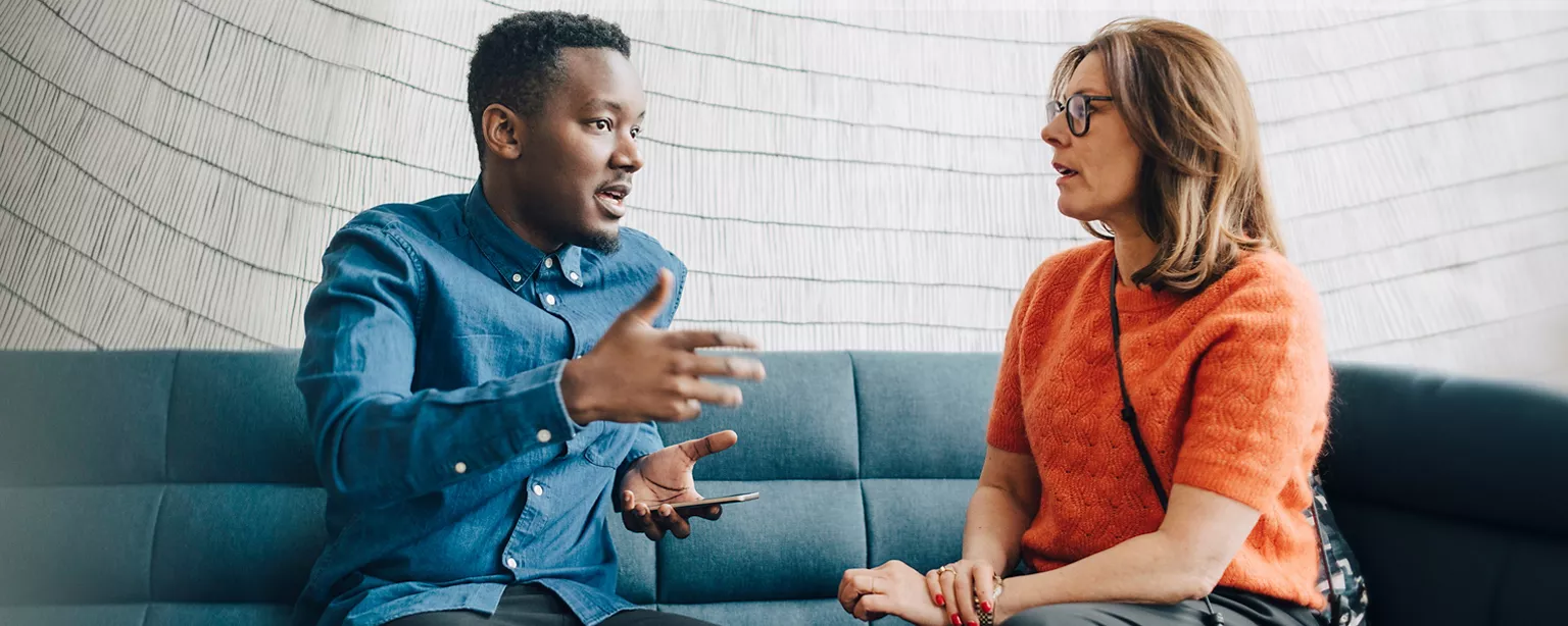 A man talking to a woman on a couch. 