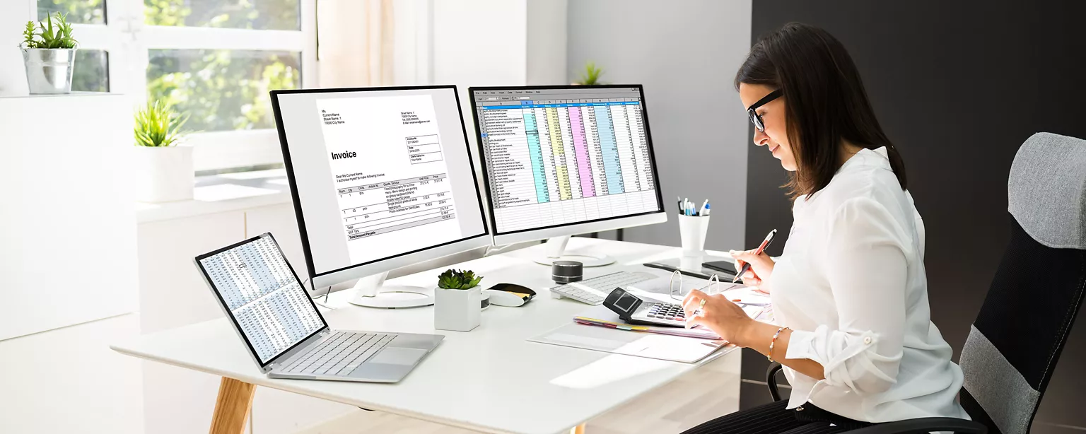 What You Need to Know About Accounting Automation — Image of robot hand pressing finger on calculator by stack of paper receipts