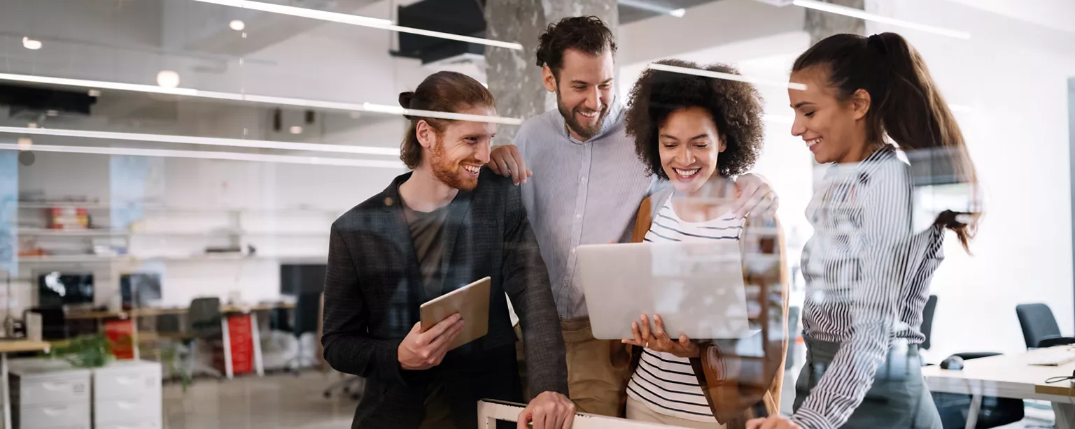 Team of people in an office, looking at a report and smiling.