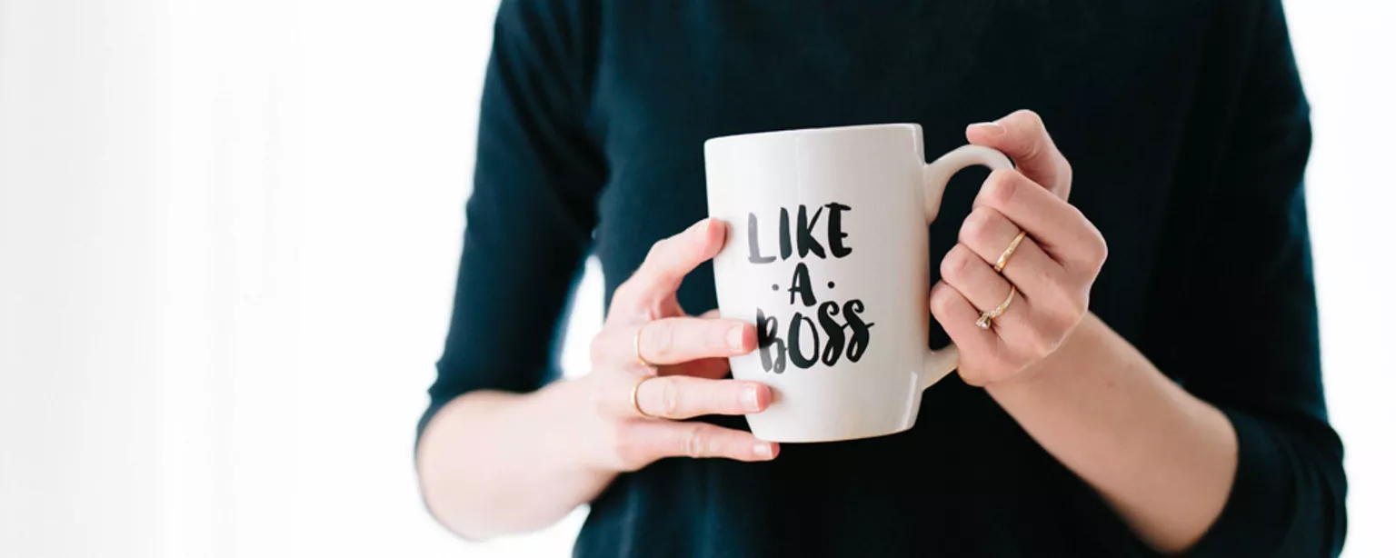 Junge Frau hält einen Becher mit der Aufschrift “Like a boss”
