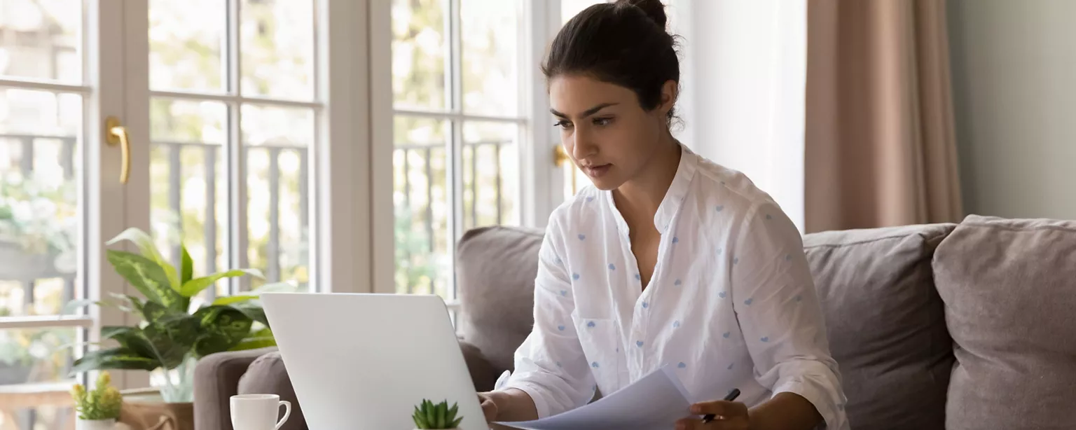 A job seeker takes notes as she researches a company where she will be interviewing.