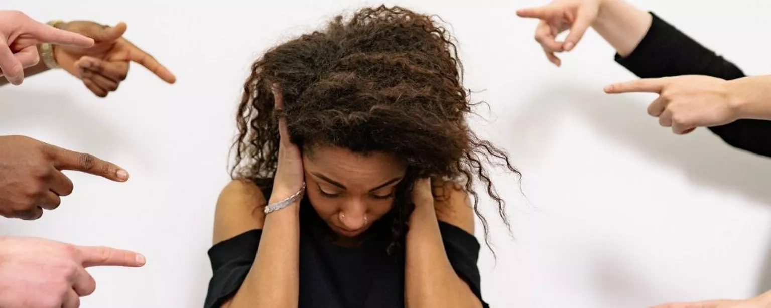 9 Finger zeigen auf Frau, die sich die Ohren zuhält