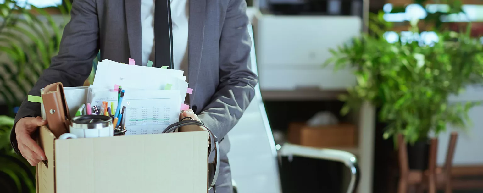 Ein Büromitarbeiter hat seine Sachen in einen Karton gepackt, da er das Unternehmen verlässt.