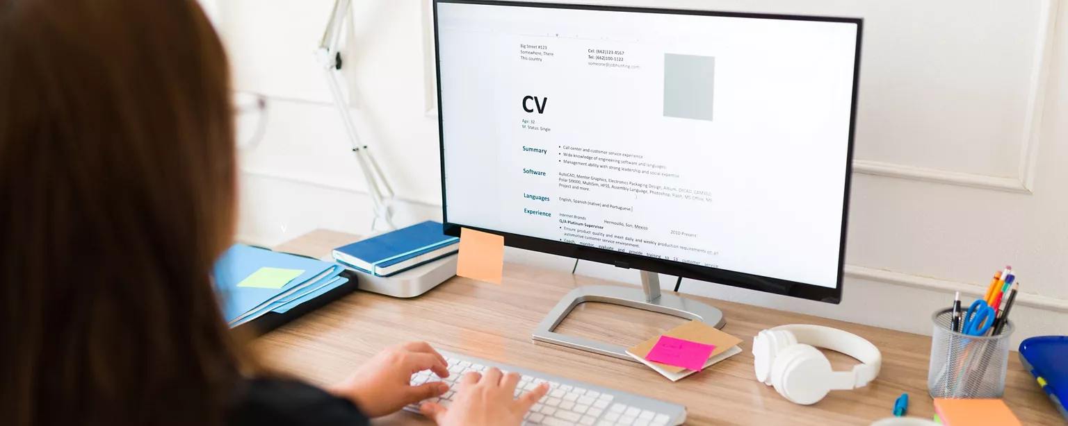 Frau von hinten, die an ihrem neuen Lebenslauf arbeitet.