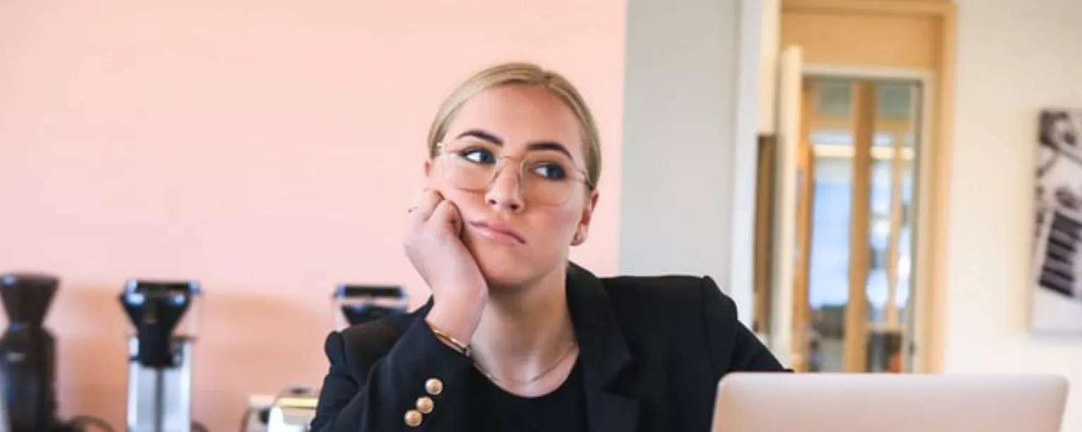 A female employee sits at home on her laptop looking fed up